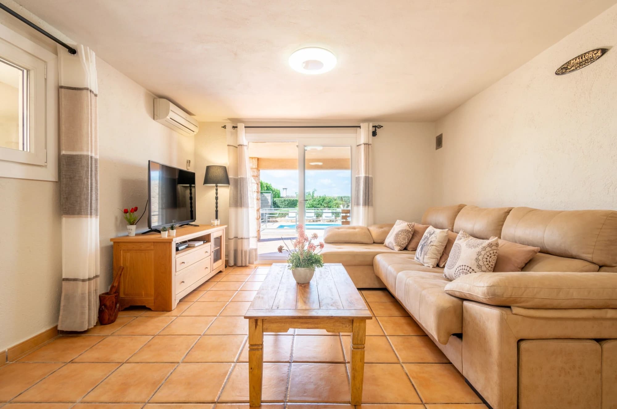 A living room with a sofa, TV, wooden table, and a view to the outside.