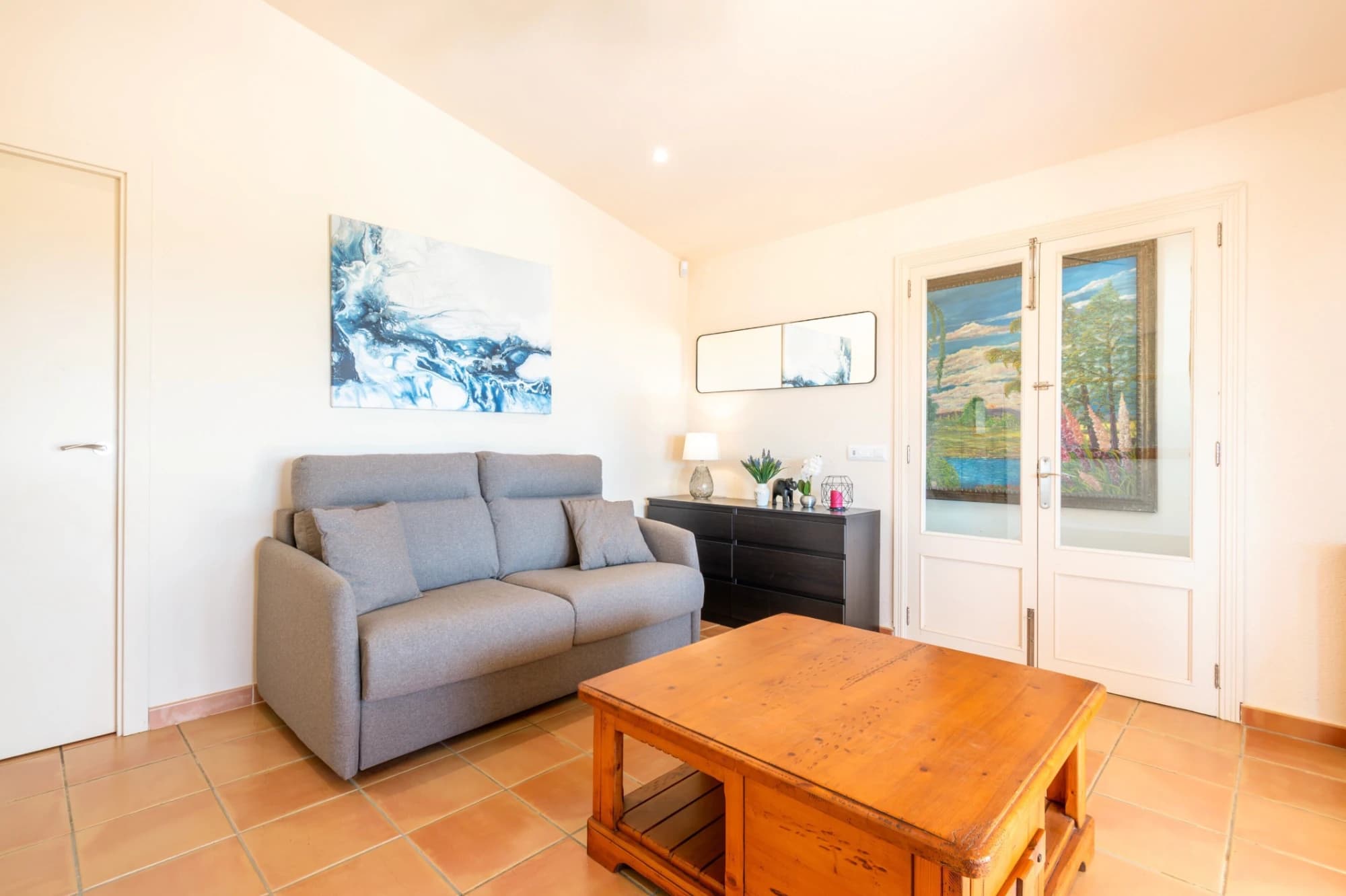 A living room with a sofa, a wooden table, a cabinet, and a painting on the wall.